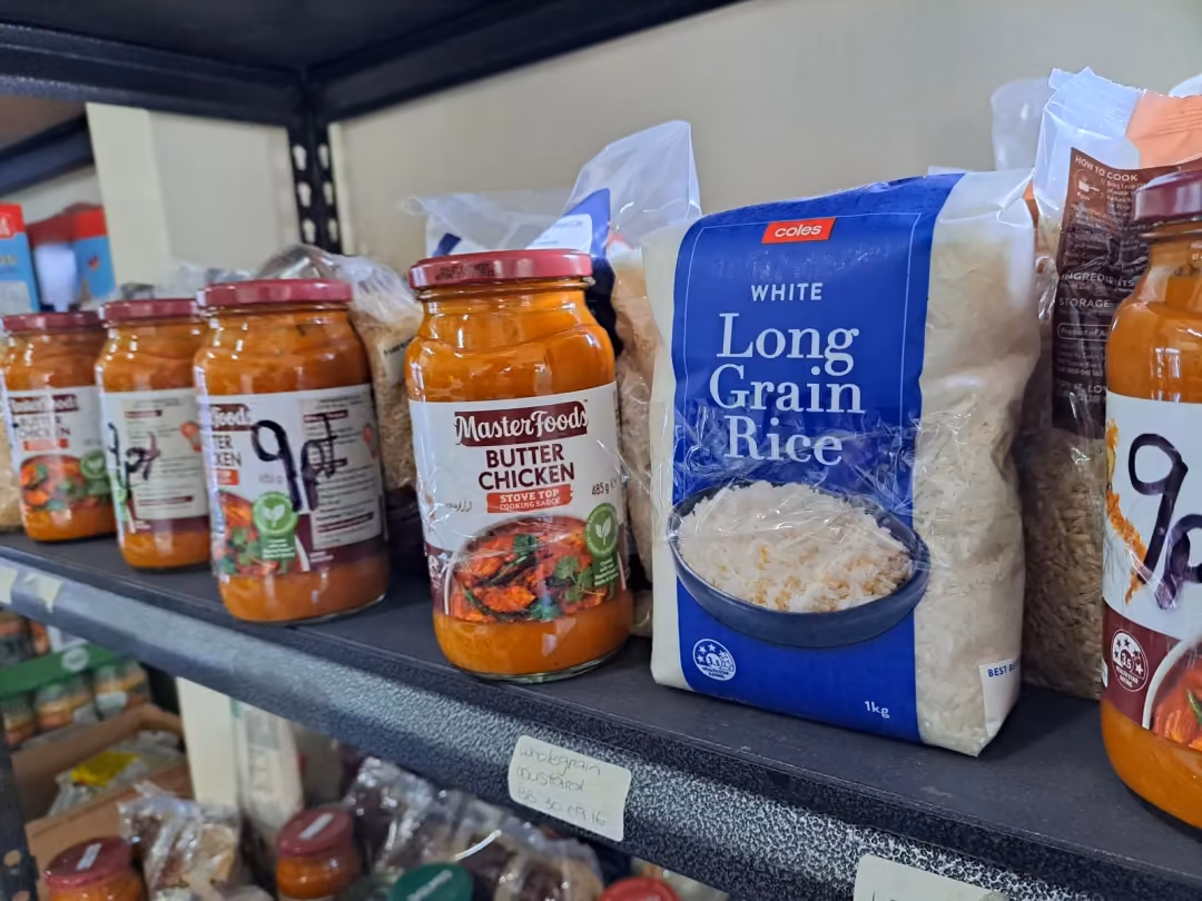 Pantry shelf stocked with rice and jars of pasta sauce