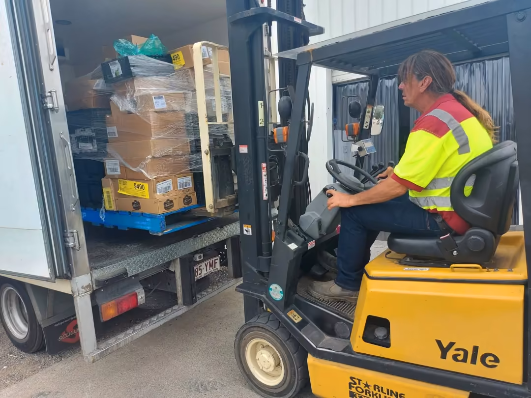 Worker driving a forklift to load a truck at the Goodness warehouse