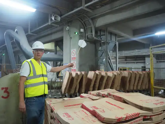 Peter Weiss observing work in an industrial setting, wearing a hard hat and high-visibility vest.