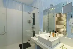 Deluxe Room bathroom at Ayurvie Weligama in Sri Lanka featuring a modern glass-enclosed shower, contemporary vanity, and bright spa-inspired design.
