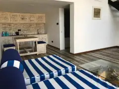 Open-plan Garden Loft at Ayurvie Weligama with two striped daybeds, a glass coffee table, and a kitchenette with dining table.