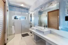 Bathroom in an Ayurvie Weligama Garden Loft room with a glass-enclosed shower, square sink vanity, and a small window.