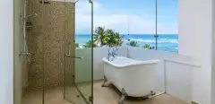 Master Suite (Sea View) bathroom at Ayurvie Weligama featuring an ocean-view tub and glass shower.