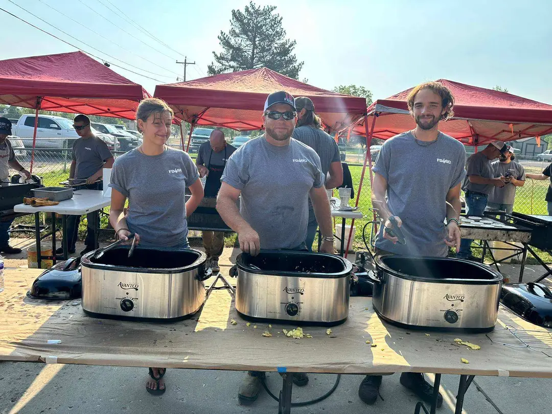 Volunteers serving breakfast from roasters under red canopies