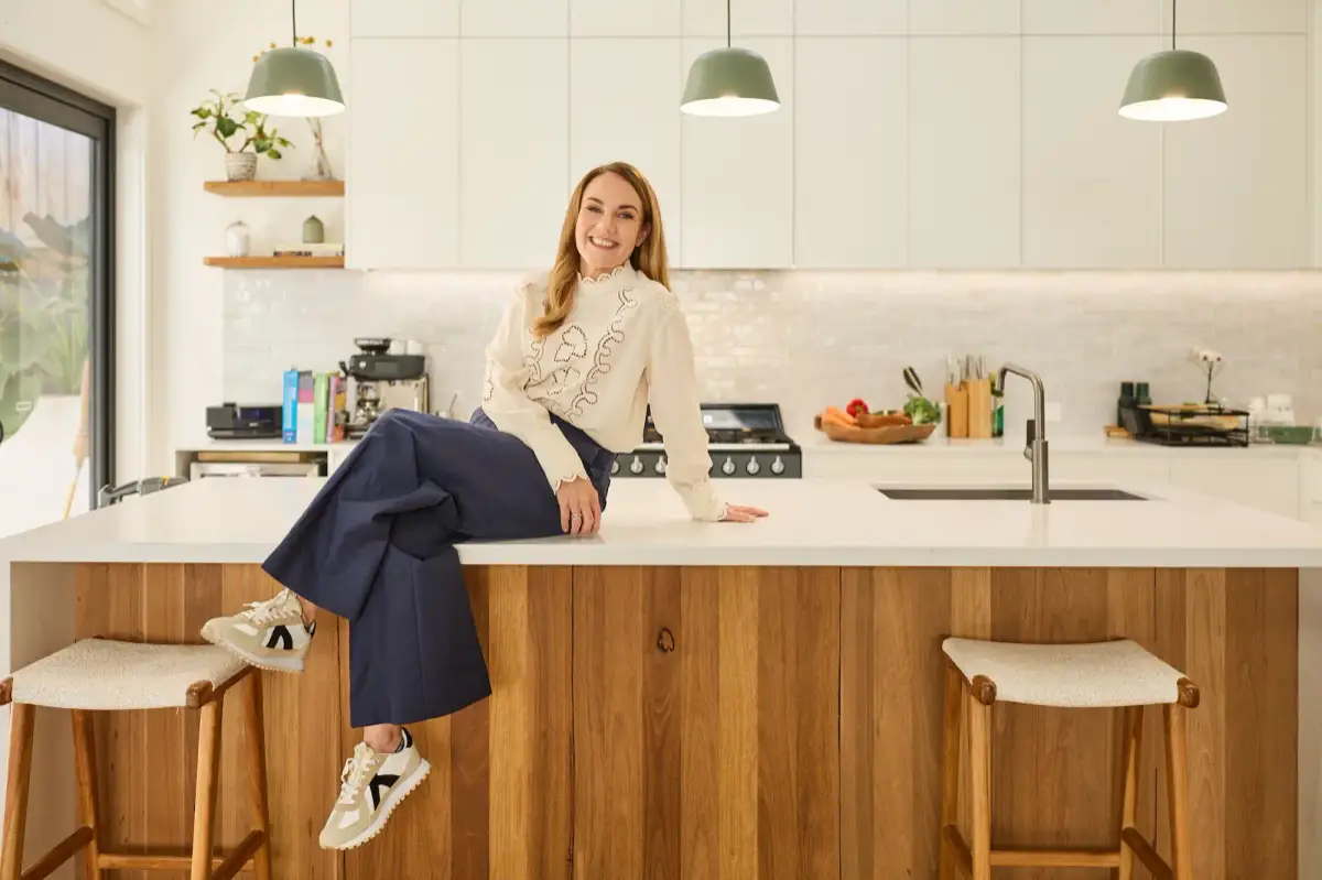 Sonia Savage, functional nutritionist, sitting on her kitchen bench