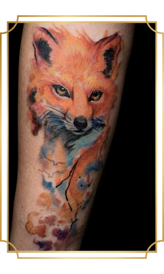 Watercolor fox portrait tattoo with vivid orange fur, blue shadows and loose paint-splash details by San Marcos artist Alek the Saint