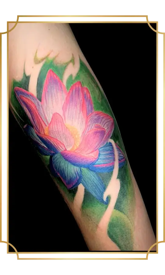 Full-color lotus forearm tattoo with glowing pink petals, purple and blue lower petals, and a saturated green botanical background by Alek the Saint