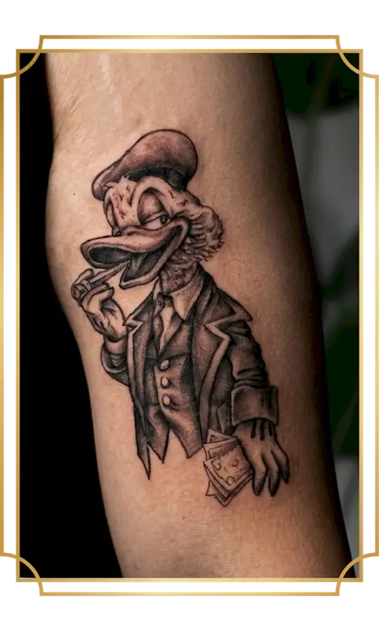Black and gray Scrooge McDuck tattoo in a suit holding money and smoking a cigar on the bicep