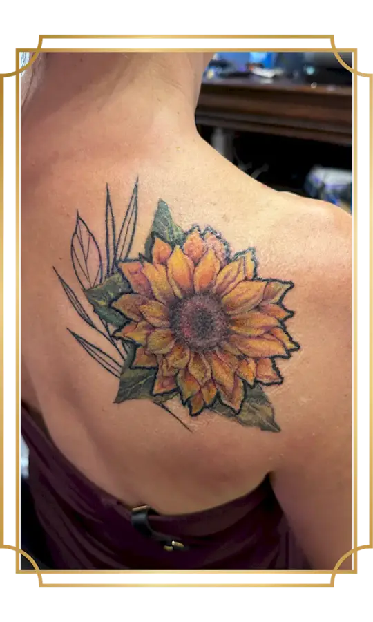 Color sunflower cover-up tattoo with orange and yellow petals, green leaves and botanical linework on the shoulder blade