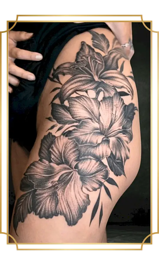 Blackwork floral tattoo with detailed flowers and leaves on the thigh