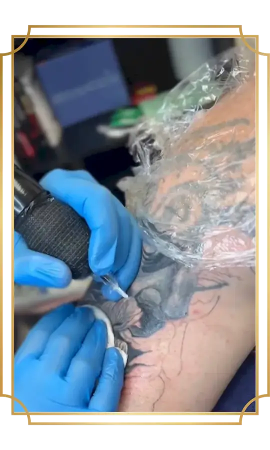 Tattoo artist working on a black and gray bearded face tattoo during a tattoo session