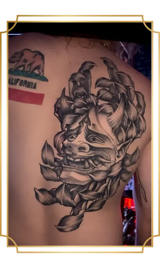 Black and gray oni mask tattoo inside a chrysanthemum on the back