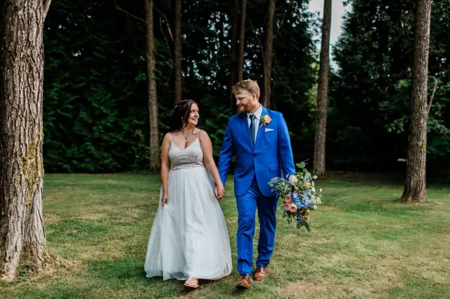 A man in a bold blue custom made-to-measure wedding suit from Cardero walking with his bride