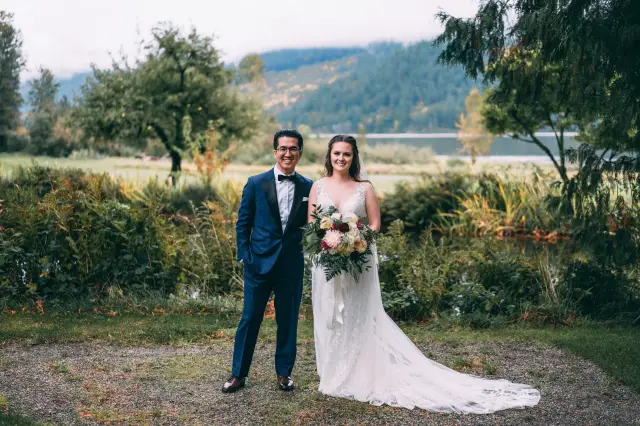 A Groom and his Bride at a Fraser Valley wedding. The bride is in a white dress while the Groom is in a custom Cardero Clothing blue tuxedo.