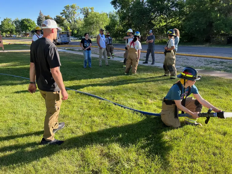 Volunteers practicing hose handling on a grass field