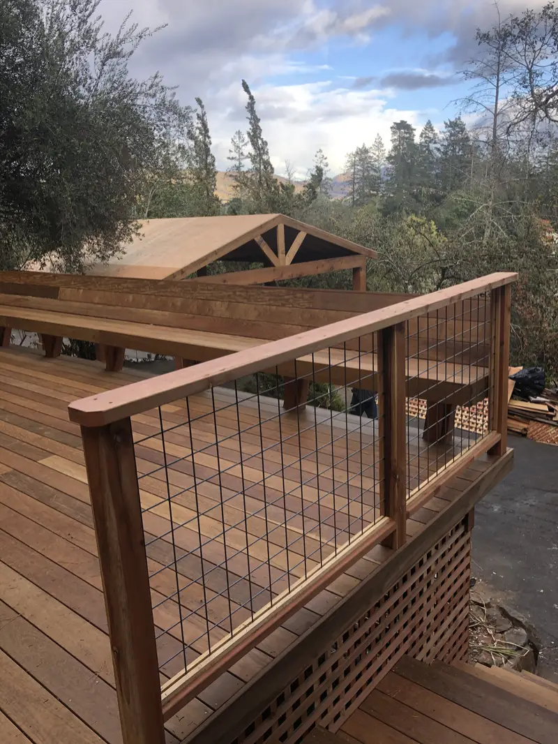 Hardwood deck with a redwood-framed welded-wire railing and lattice skirt, gabled cover and hills beyond