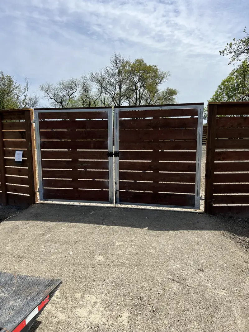 Double driveway gate with galvanized steel frames and horizontal stained redwood infill, set in a matching horizontal board fence
