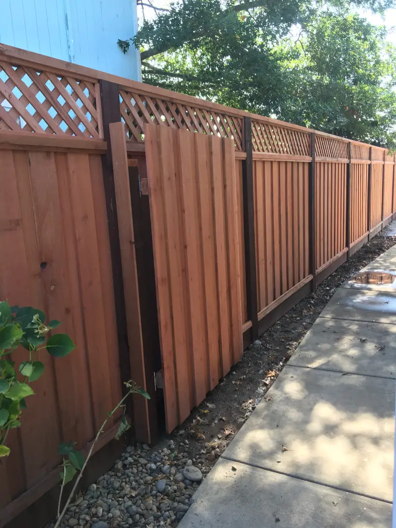 Lattice-top redwood privacy fence with a matching walk gate along a concrete side path