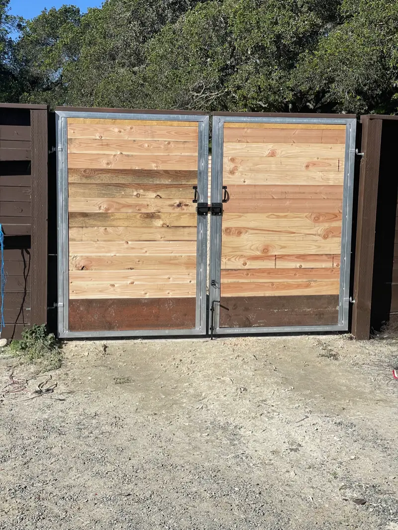 Double driveway gate with galvanized steel frames and natural horizontal Douglas fir infill, set in a dark-stained horizontal fence