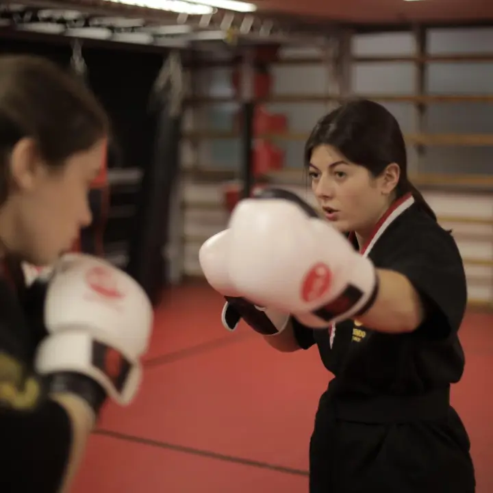 Alumna con guantes en posición de guardia durante un entrenamiento de defensa personal en un centro Mugendo de Barcelona