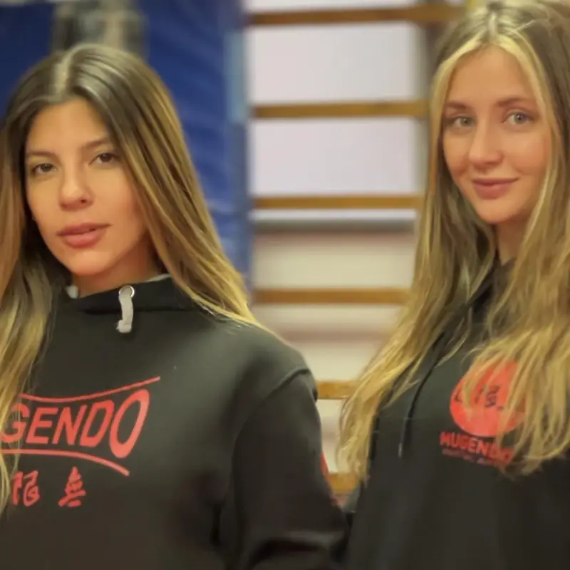 Dos alumnas con sudadera de Mugendo en la sala de entrenamiento