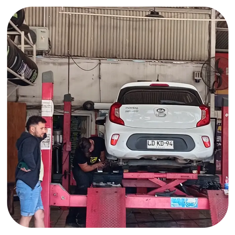 Cliente mirando cómo trabajan en su auto en el elevador