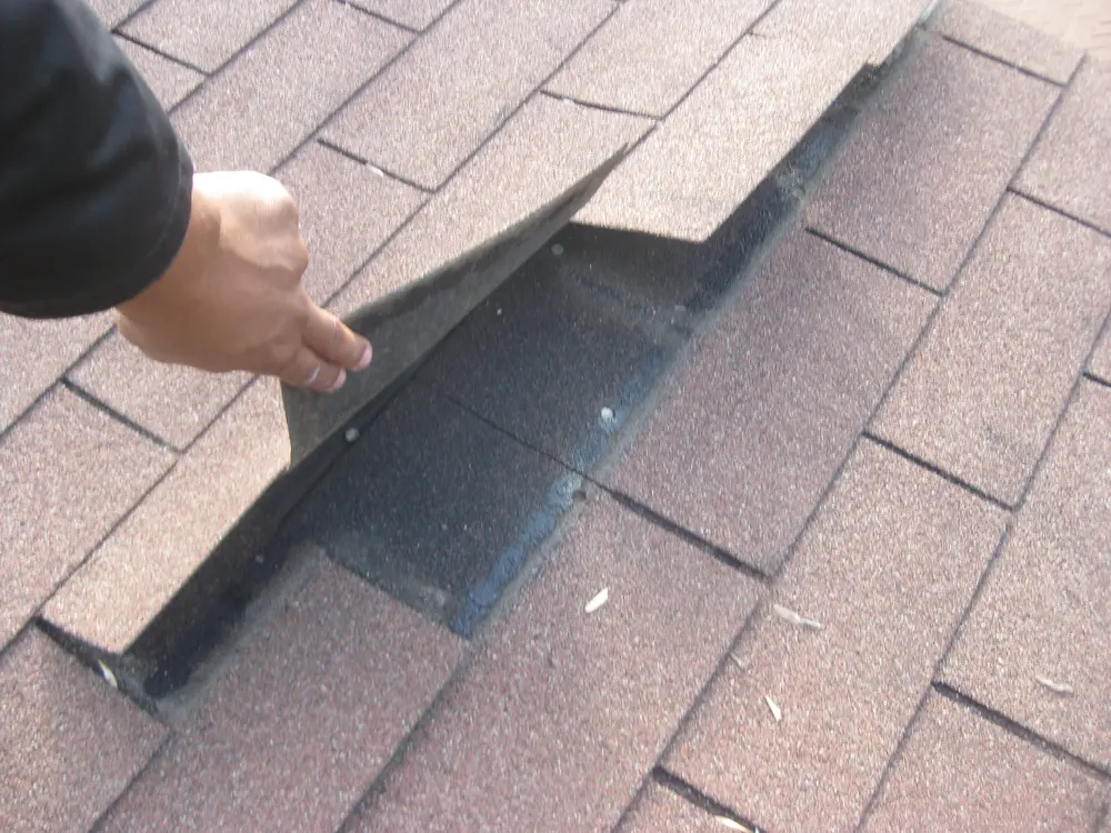 Wind-lifted shingle checked by hand during a Repair King inspection