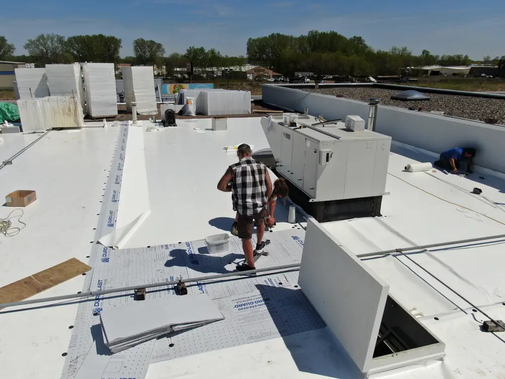 Repair King crew flashing rooftop equipment on a white PVC commercial roof