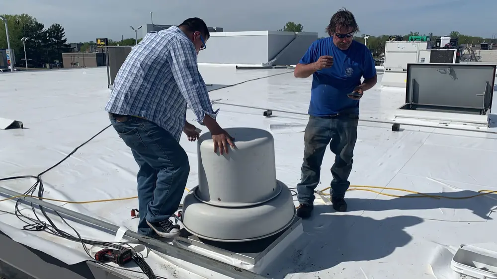 Repair King crew repairing the flashing around a rooftop fan on a flat roof
