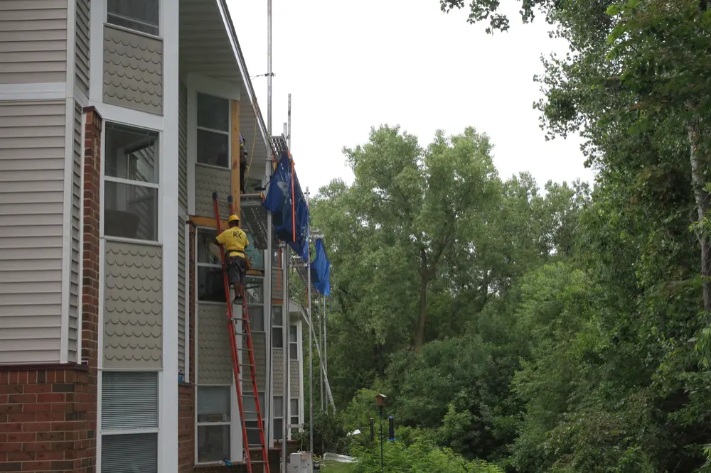 Repair King crew on a ladder working on siding at an Oakdale, MN senior living building