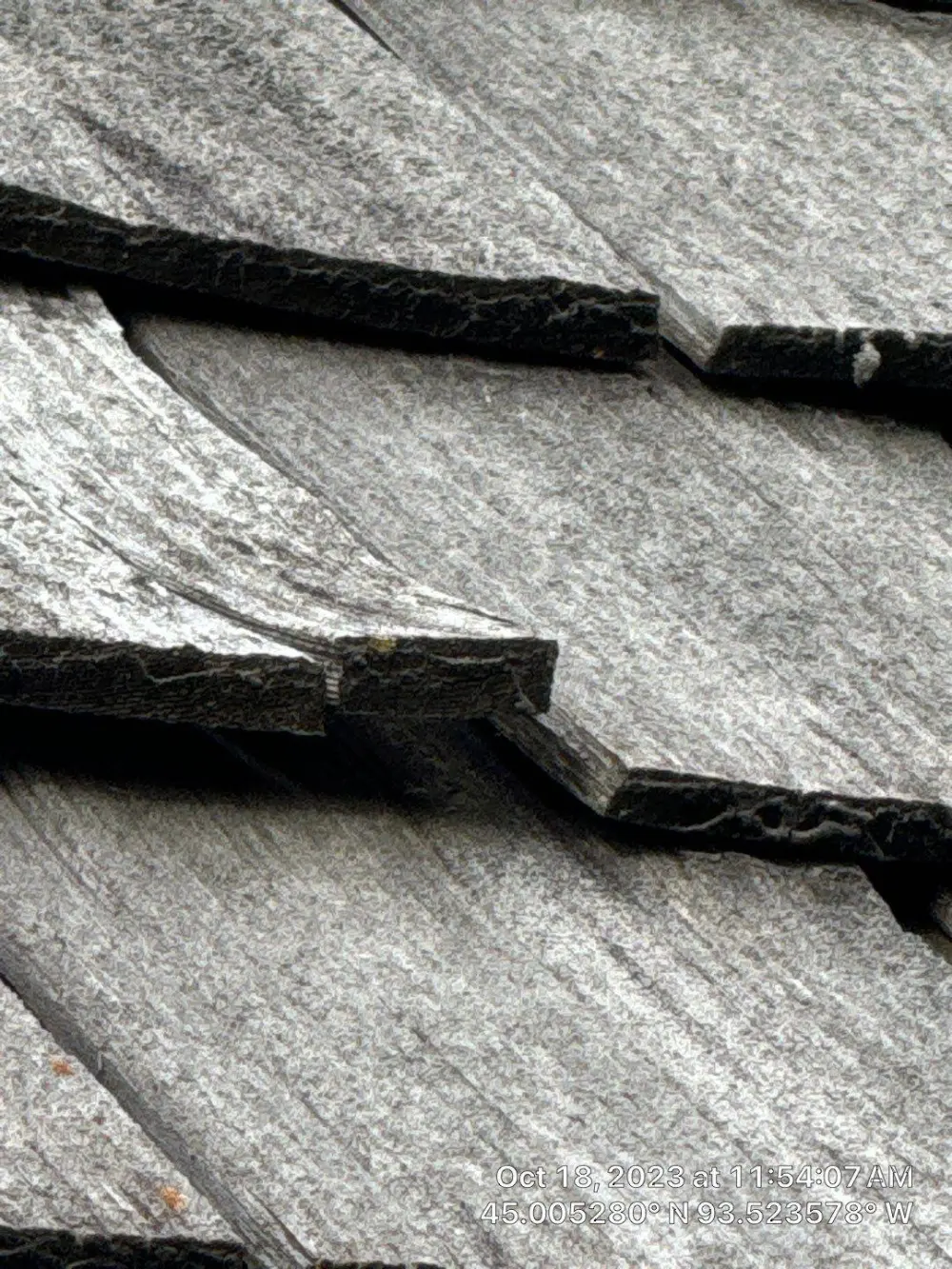 Split, weathered cedar shakes on an older roof