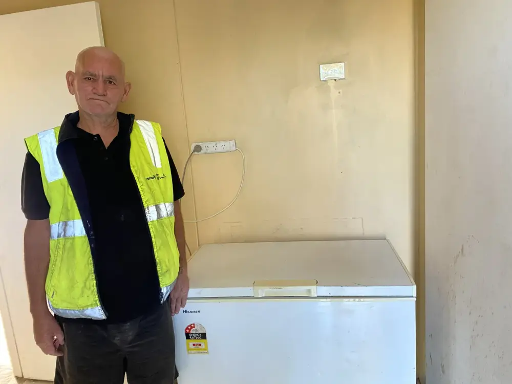 Goodness volunteer in hi-vis standing beside a chest freezer