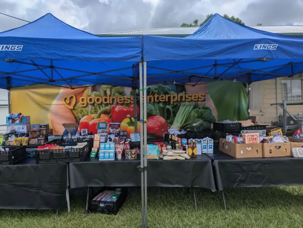 Goodness Enterprises marquee and fresh produce stall at an outdoor community market