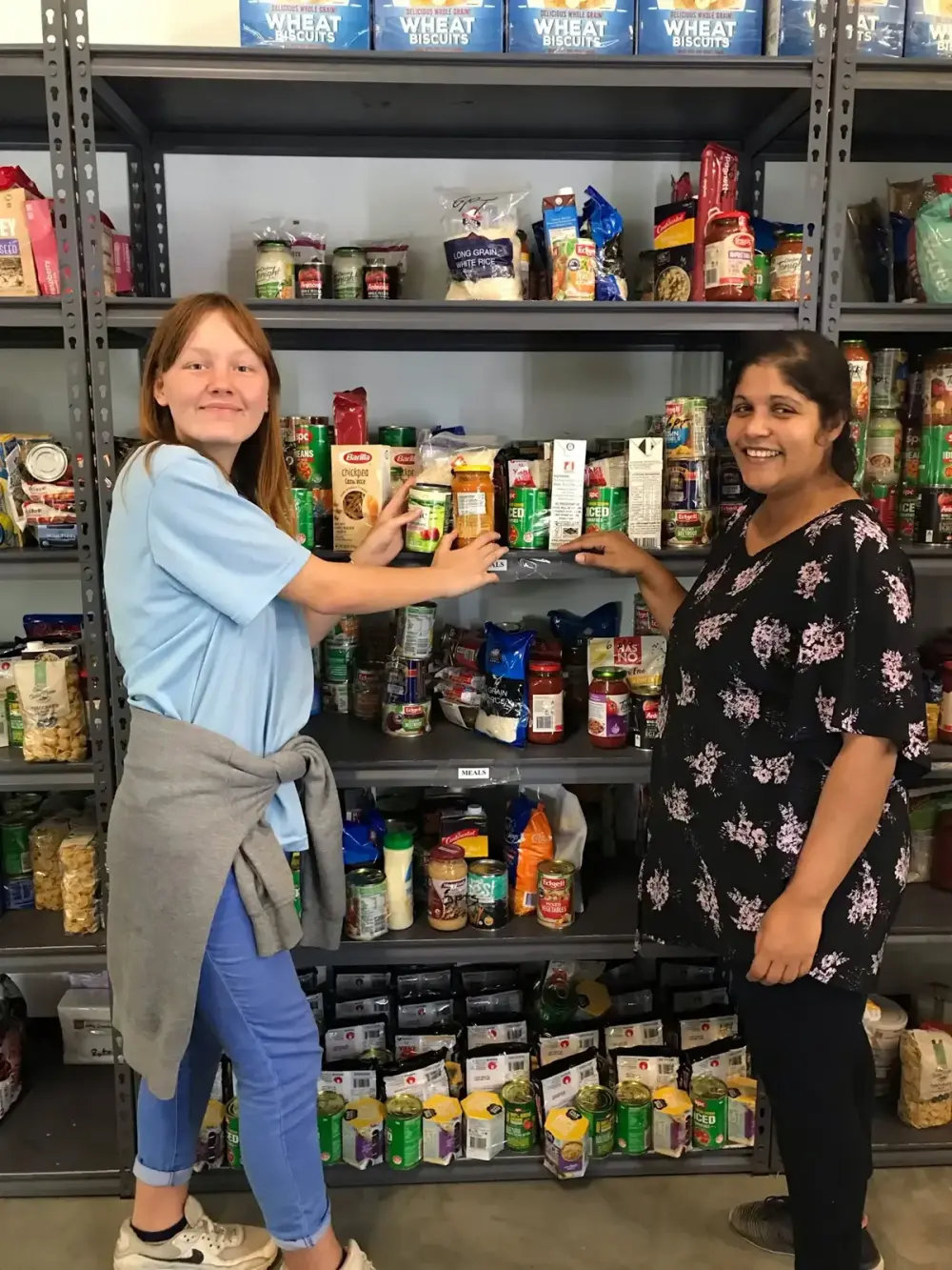 Two Goodness team members stocking pantry shelves