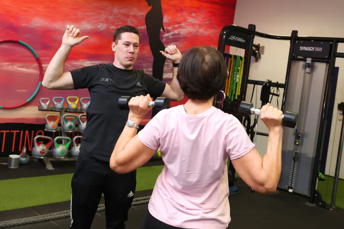 Een coach begeleidt een deelnemer bij een oefening bij Sporty-x
