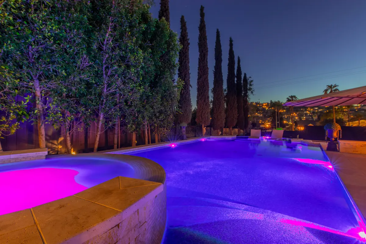 Purple-lit pool and spa at dusk
