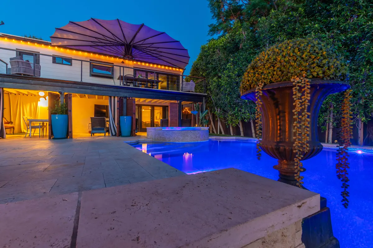 Resort-style courtyard pool with umbrella and warm evening lighting