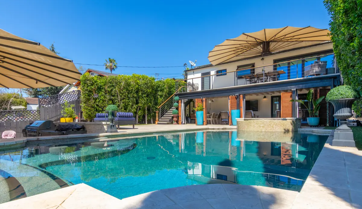 Pool in front of a two-story home with sunshade