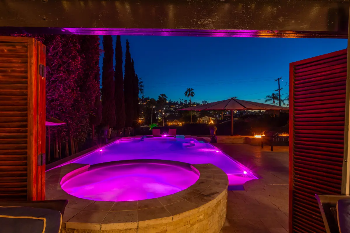 Cabana view of a glowing spa and pool at night