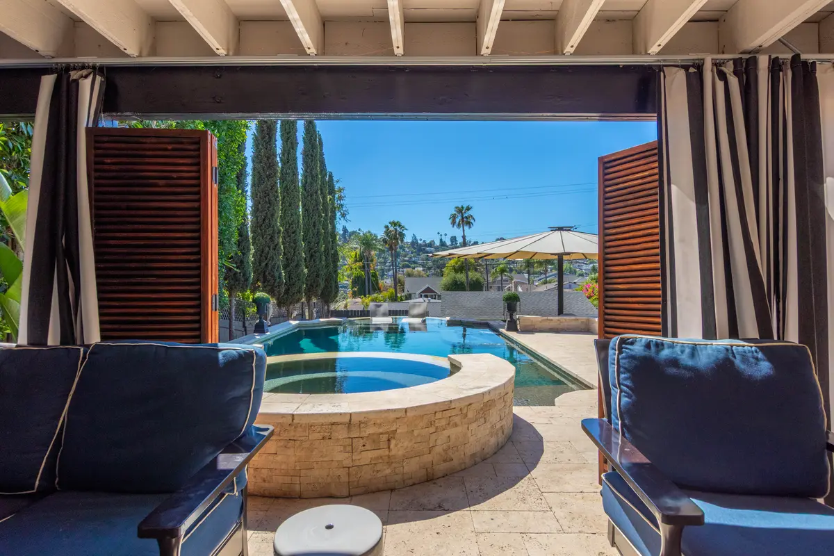 View from a shaded cabana onto a stone spa and pool