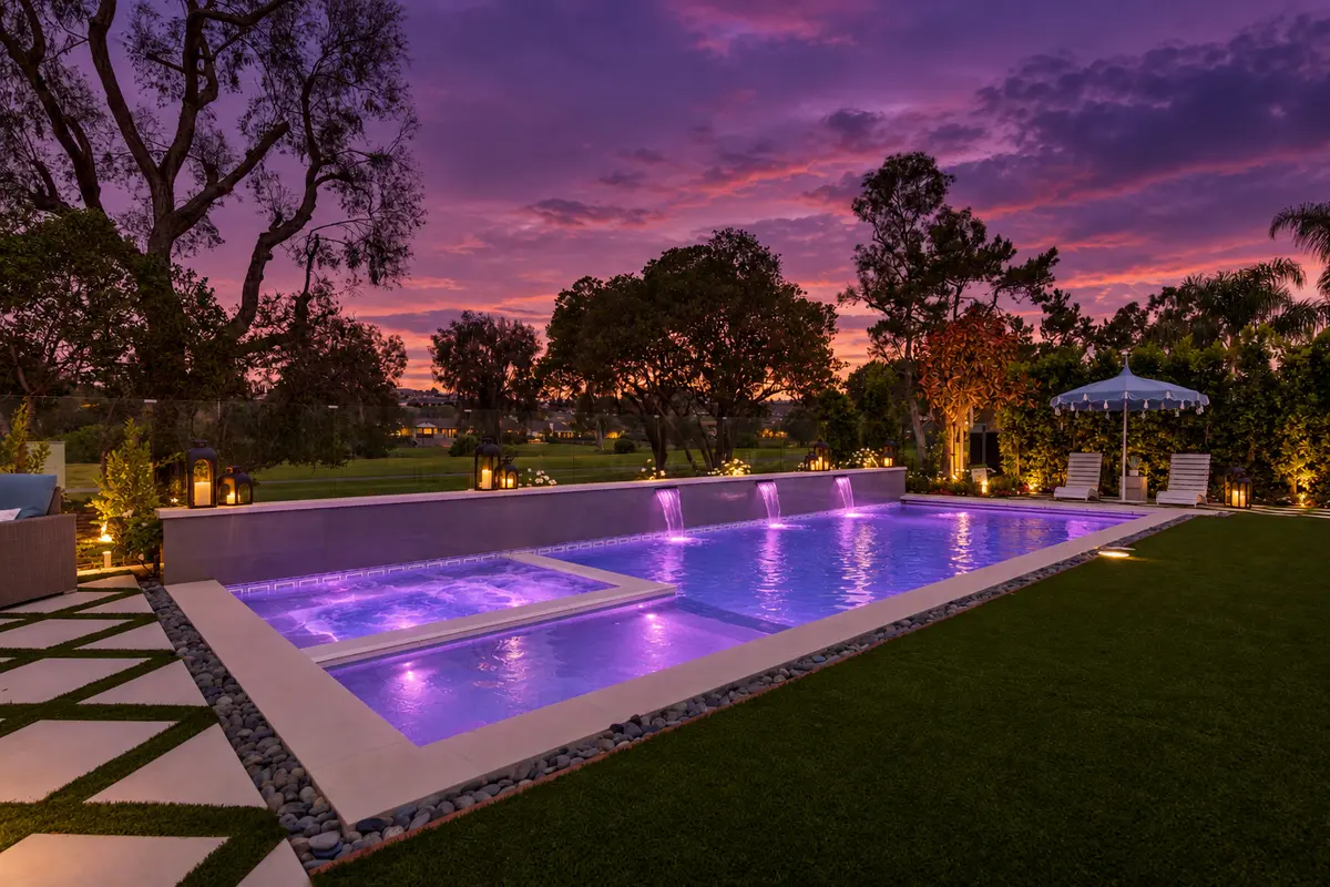 Lit pool and spa under a sunset sky