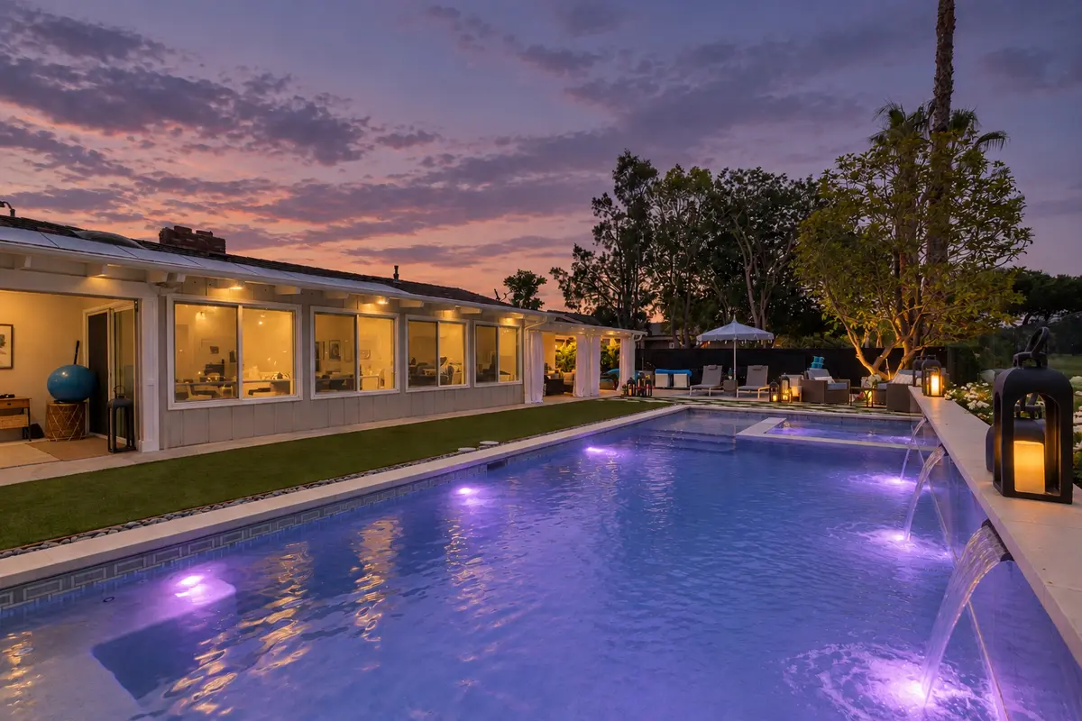 Long lit pool beside a home at twilight