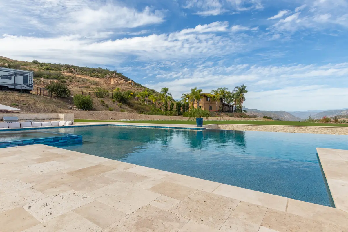 Sunken fire pit lounge with white sectional beside the pool