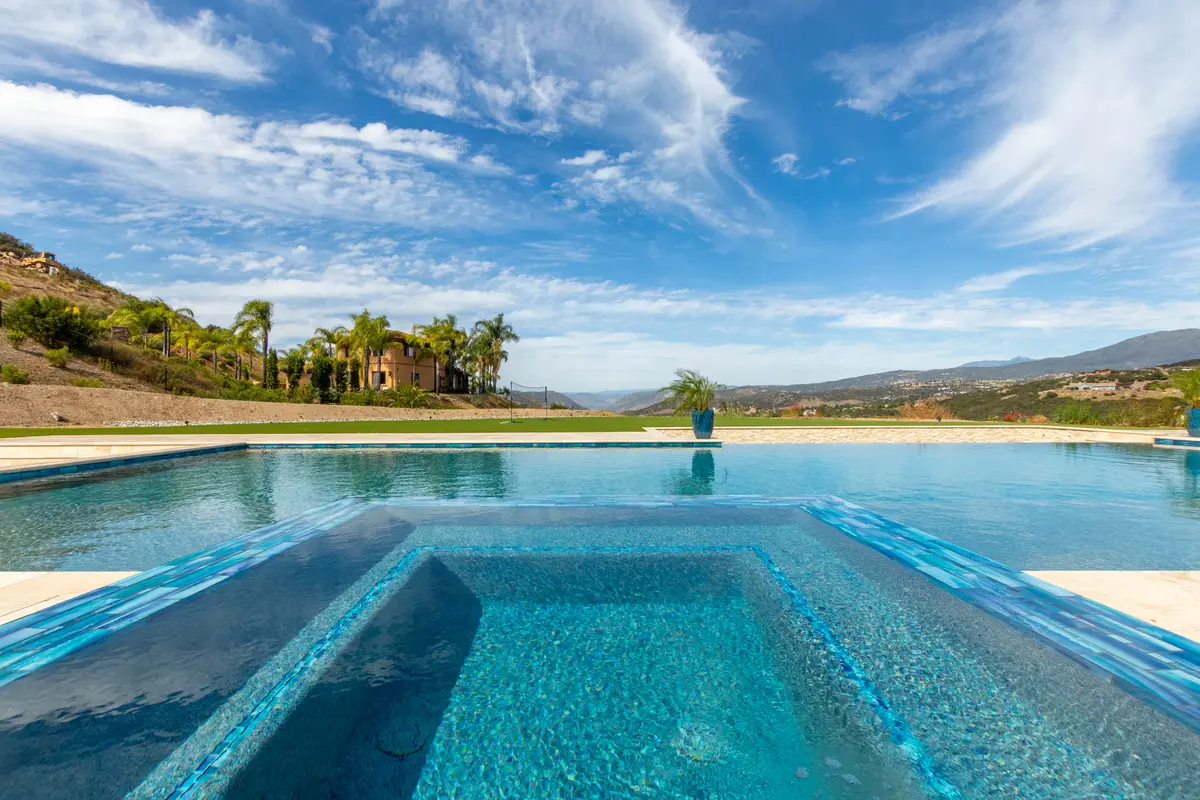 Glass-tile pool edge under a bright blue sky