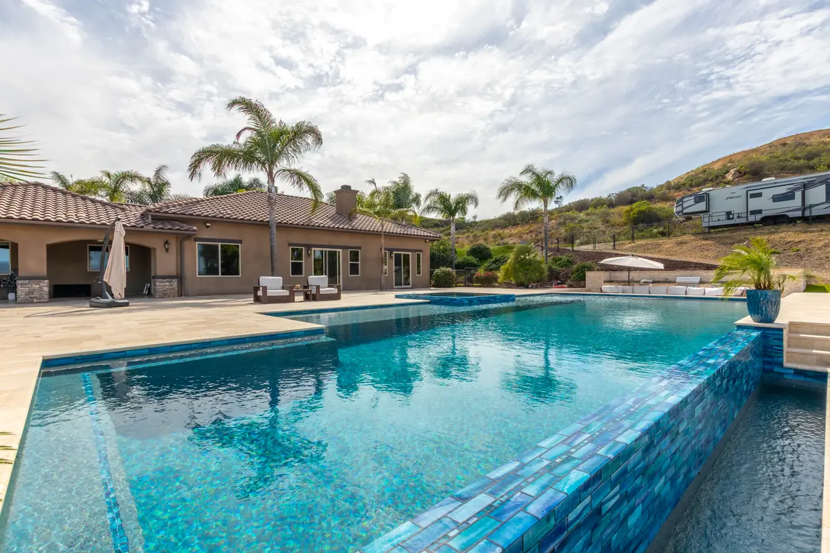 Large glass-tile pool beside a hillside home