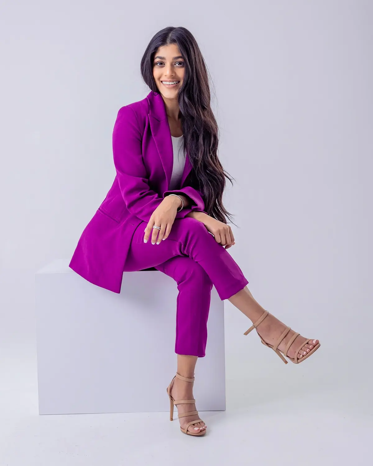 Amber Farooqui seated in a purple suit