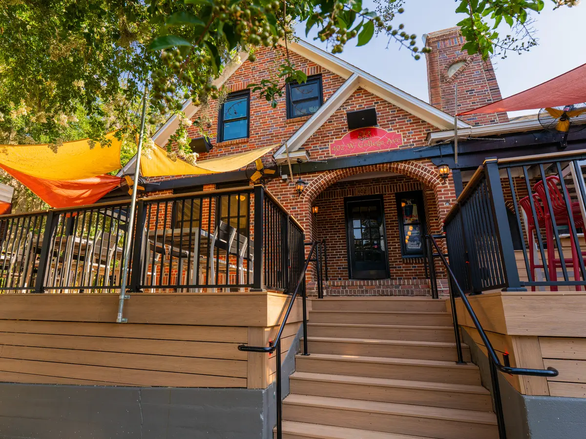 The Brick House front steps on College Avenue, red sails over the patio