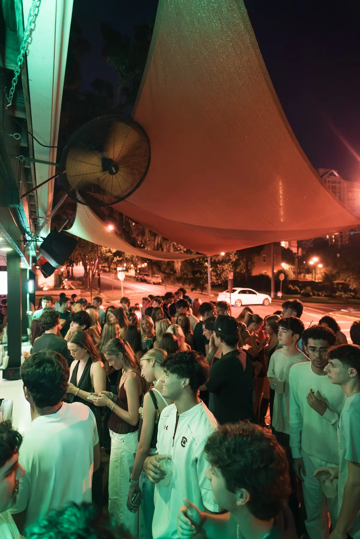 Packed patio at night under the sails