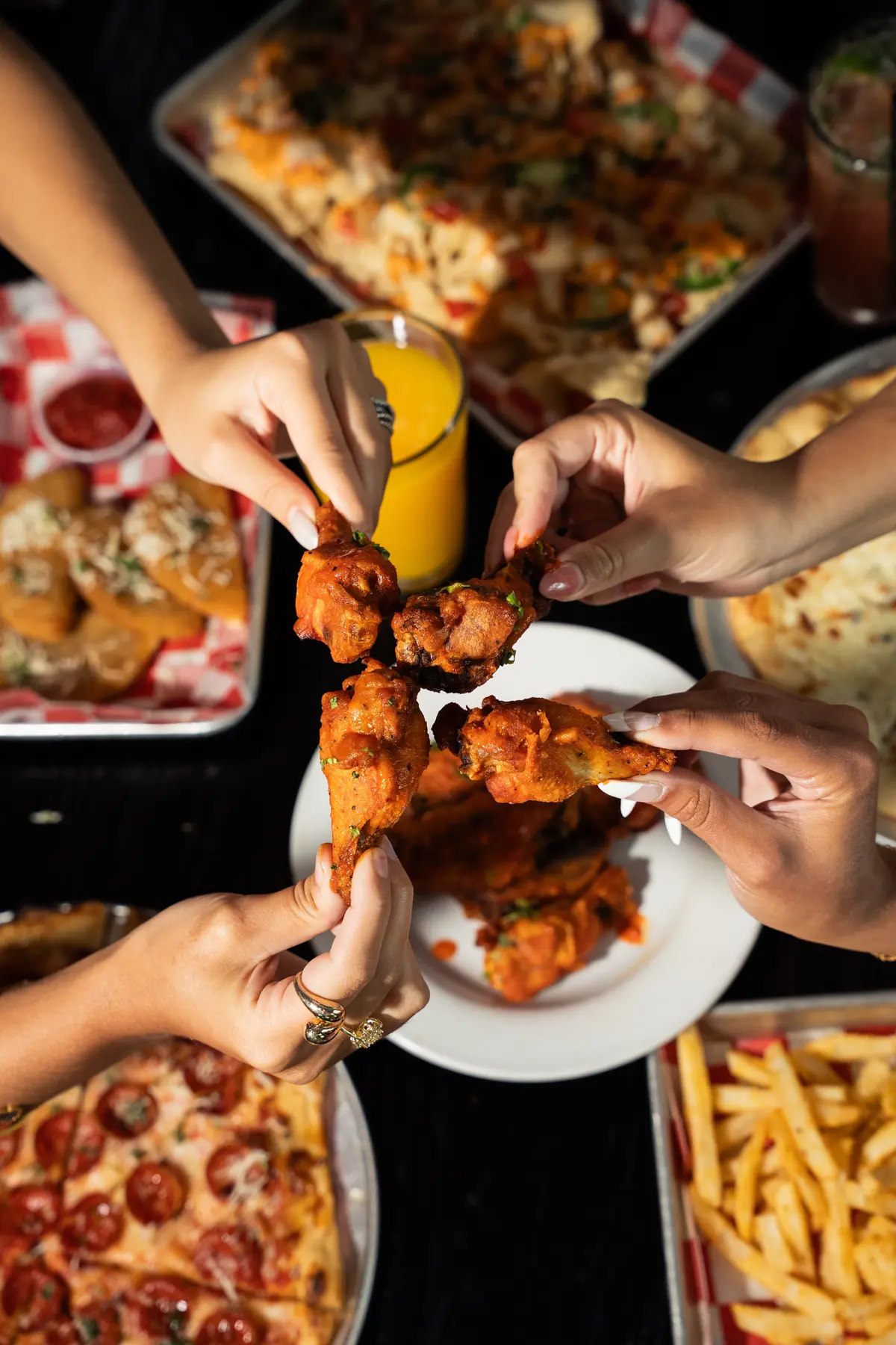 Hands reaching for a plate of wings