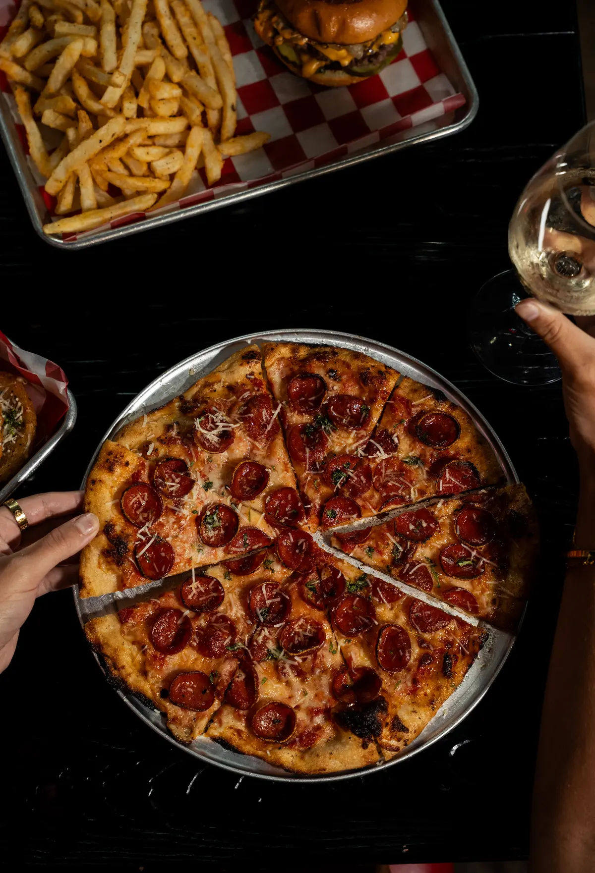 Pepperoni pizza with fries and drinks on the table